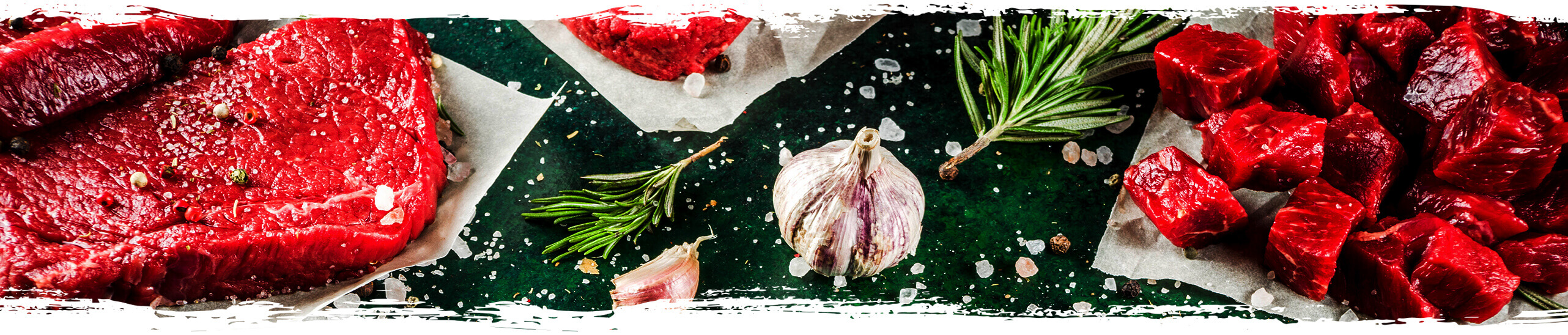 Hofschlachterei Fleischstücke, Knoblauch, Rosmarin und Salz von oben fotografiert.