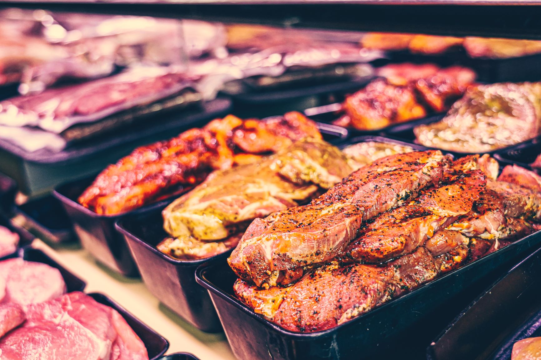 Mariniertes Fleisch Mariniertes Fleisch liegt in schwarzen Schale in der Theke.